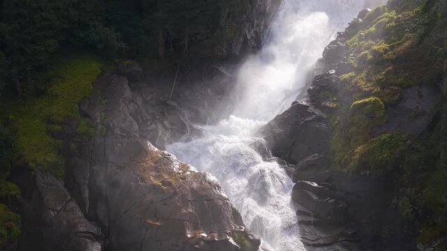 Breathtaking drone footage capturing the sheer power of Krimmler Wasserf&auml;lle in the Austrian Alps. Golden sunlight pierces through the misty spray against vibrant mossy rocks