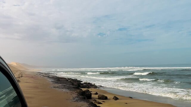 Sandwich Harbour in Namibia at the coast of the Atlantic Ocean. Sandy beach. Sandwich Harbor roundtrip daytime car tour