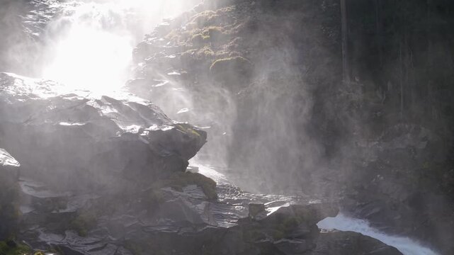 Breathtaking drone footage capturing the sheer power of Krimmler Wasserf&auml;lle in the Austrian Alps. Golden sunlight pierces through the misty spray against vibrant mossy rocks