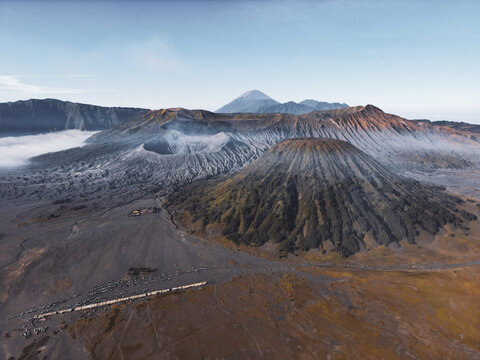 Aerial view of the rugged, volcanic landscape, with Mount Bromo's caldera casting long shadows across the barren plains, Java, Java, Indonesia.