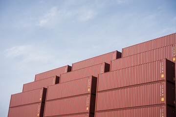 Stacked red shipping containers at a port freight yard under clear sky