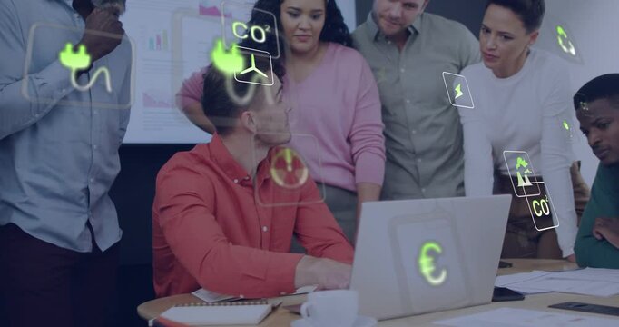 Seated man typing, pausing, speaking and pointing at laptop, team leaning in, energy icons drifting