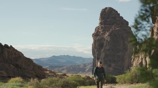 Traveler with a backpack hiking through the Piedra Parada natural protected area in Chubut, Patagonia Argentina, near massive volcanic rock formations