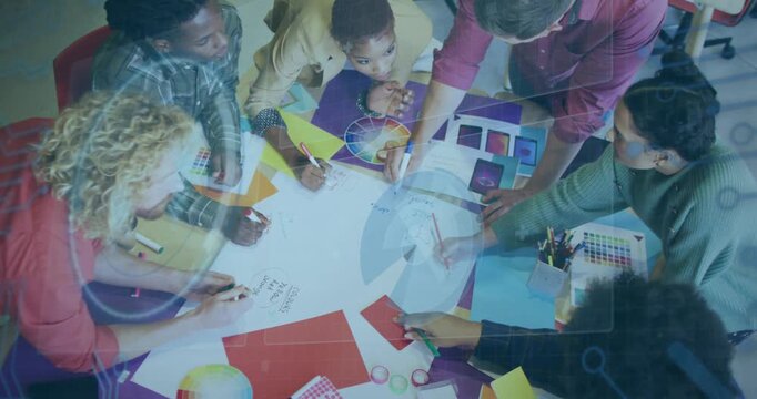 Design team leaning in sketching on big sheet after color wheel cue tracing circle refining palette