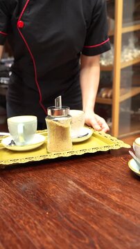 Professional waitress serving two cups of coffee with organic panela sweetener