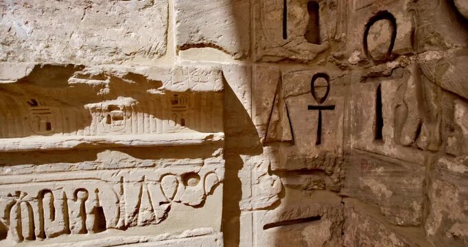 Closeup of ancient Egyptian hieroglyphic inscriptions with cartouches and bird symbols carved in sandstone wall at Medinet Habu temple in Luxor Egypt, detailed royal text.