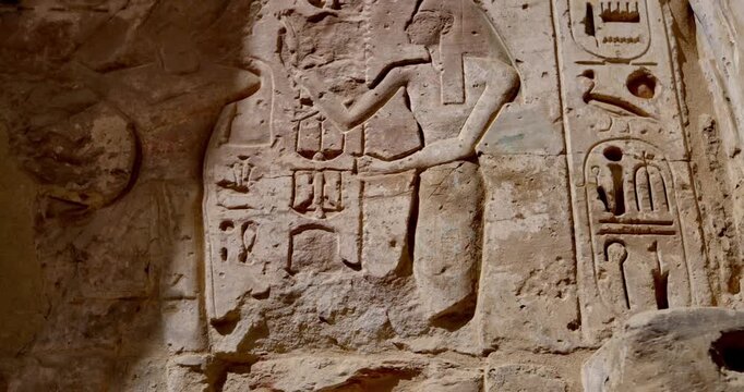 Closeup of ancient Egyptian hieroglyphic inscriptions with cartouches and bird symbols carved in sandstone wall at Medinet Habu temple in Luxor Egypt, detailed royal text.