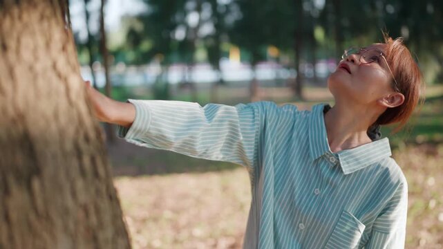 Happy elderly female citizen enjoying a peaceful morning in nature while practicing mindfulness and deep breathing to improve her health and vitality in a green forest during retirement