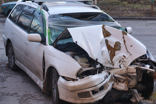 This image captures a broken-down white car, abandoned and slowly rusting away. Nature has reclaimed the vehicle, creating a melancholic scene that tells a story of neglect and time passing.