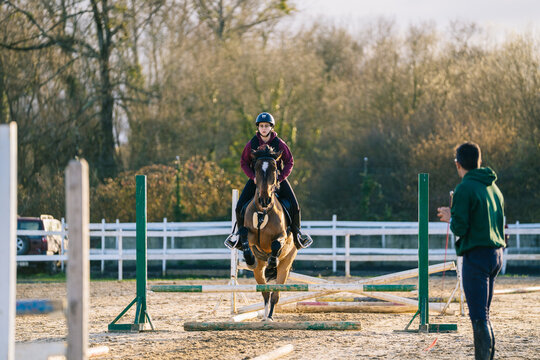 Young woman rider training horse jumping during equestrian sport