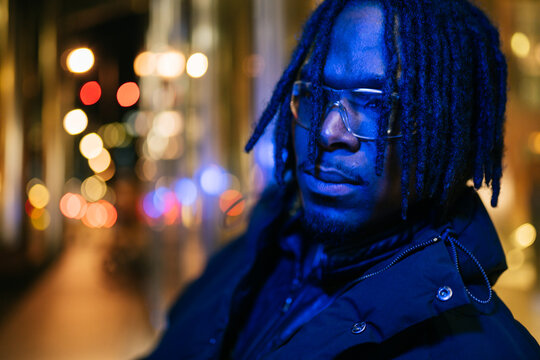 African American man standing in cyberpunk blue night city