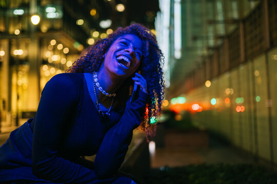 Young woman laughing enjoying city nightlife communicating