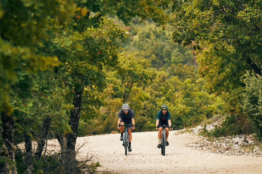 Front Facing Gravel Cyclists Riding Together On Forest Track