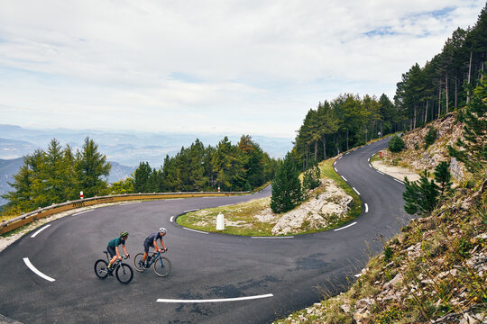 Two Road Cyclists Climbing Mountain Switchback Pass