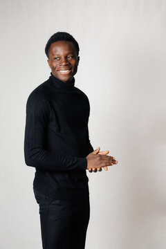 Young man smiling with his hands clasped in a studio