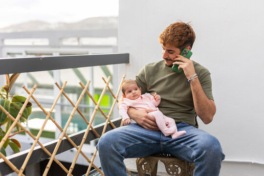 A man holds his baby on the terrace