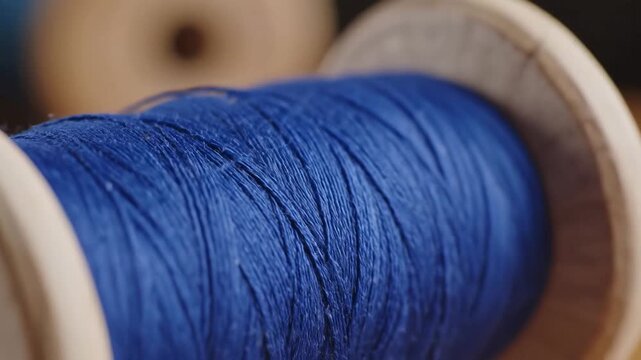 Closeup macro shot of a wooden spool filled with vibrant blue thread showcasing the texture and detail of the fibers perfect for craft and sewing concepts.