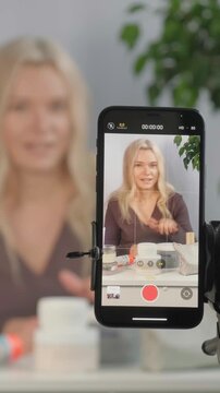Beauty Influencer Vlogging, Advice with Content Creator, Promotion for Cosmetics Product Live Streaming. Blonde Woman Recording Skincare Tutorial On Smartphone, Jars Of Cream, Serum, Framing Closeup