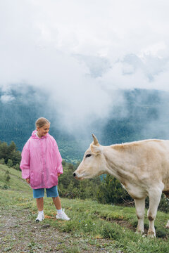 Girl interacts with cow in mountains on a cloudy day