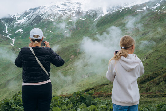 Family members take pictures of mountains with clouds