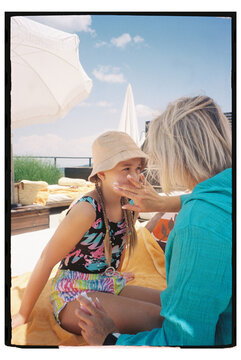 Child gets sunscreen applied at a sunny rooftop pool area
