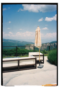 View of a landscape from a terrace with seating and an umbrella