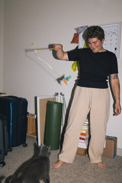 Queer woman playing with cat