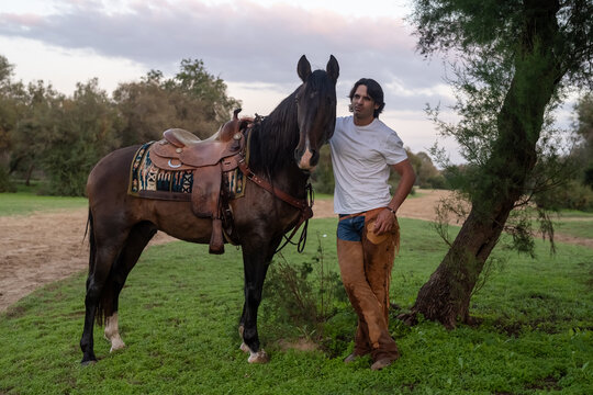 Cowboy Standing Beside Tamed Mustang In Countryside