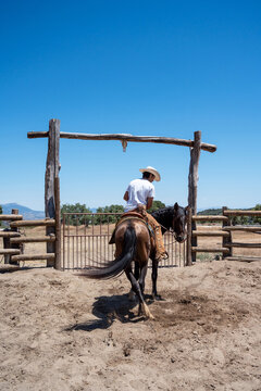 Cowboy Riding Horse Toward Ranch Gate Under Blue Sky