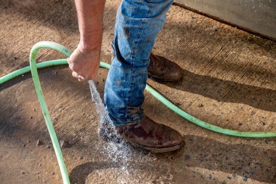 Cowboy Washing Muddy Boots With Hose