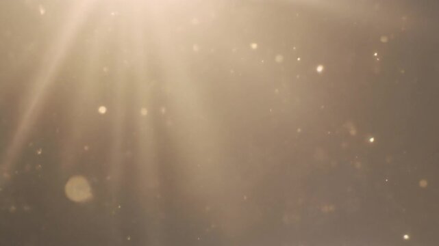 Golden dust particles floating in cinematic light rays create a warm abstract background for luxury presentations, spiritual videos, or atmospheric film overlays in high definition video production.