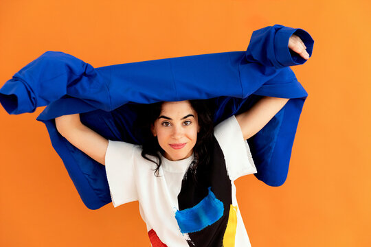 Woman smiling holding blue jacket over head