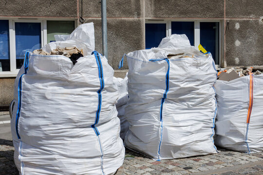 Large white bags in front of a house wall with windows