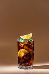 Cuba Libre in a glass with brown rum, cola, mint and lemon on light background with natural light...