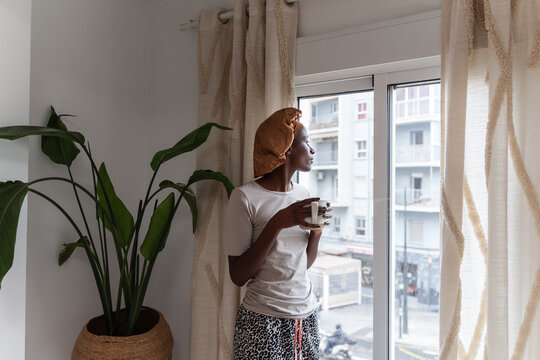 Woman looking at window and drinking coffee