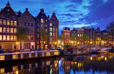 Obraz premium Amsterdam, Netherlands. Houses with nighttime illumination over canals with water in Old town. Quarter with traditional dutch houses. Night landscape. Blue hour.