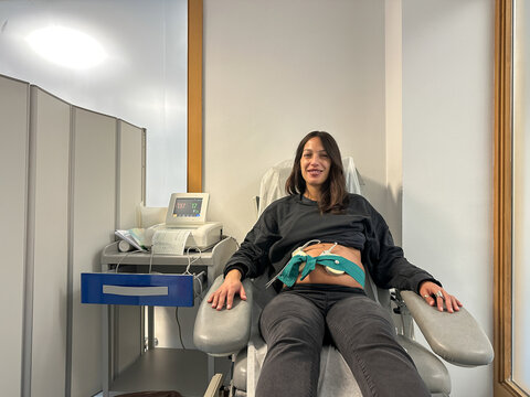 Pregnant Woman Smiling During Fetal Monitoring At Hospital