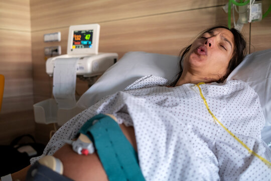 Pregnant Woman Pushing During Labor With Monitors In Hospital