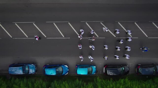 Aerial view of people in uniform walking in formation near parked cars