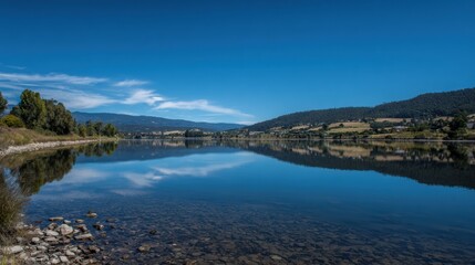 Wide Lake With Clear Water Under Blue Sky and Distant Hills Reflecting on the Water in a Natural Landscape