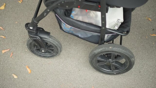 Mother steadily guides pram safely. Child caregiver vigilantly navigates uneven sidewalk surface. Thoughtful caregiver cautiously steers pram across cracked and uneven urban pavement path