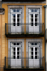 Obraz premium Symmetrical mustard building facade with balconies and white windows. 