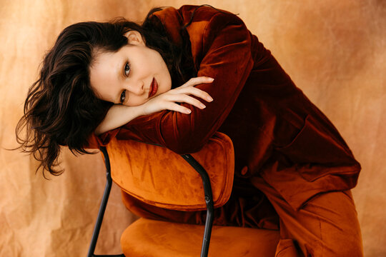 Young woman confidently posing in rust velvet suit