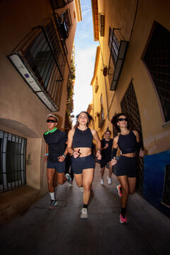 Group of runners training in a narrow alley during early morning