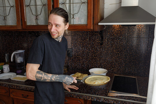 Laughing man frying pancake