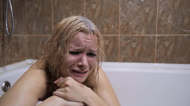 Emotional distress, psyche disorder, isolation or abuse situation. Blonde woman crying in bathtub, tears running down face, smudged makeup, pained expression, bathroom, despair, depressed condition