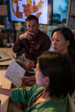 Team analyzes data, map, and charts in a meeting.