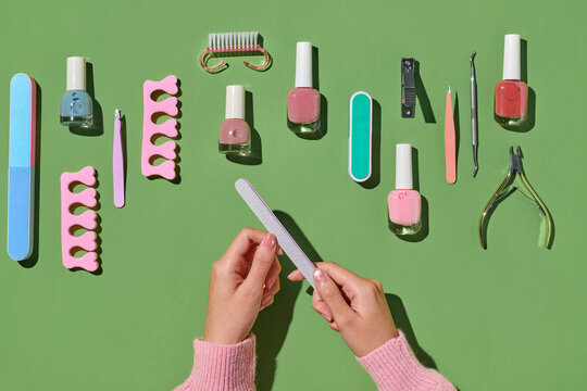 A set of nail care tools arranged on a bright green surface