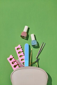 A manicure kit with nail polish, tools, and accessories on green