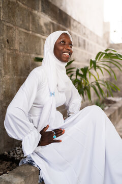 African woman wearing white hijab smiling and sitting